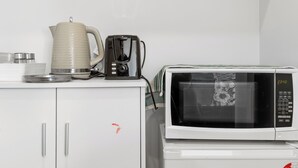 A kitchenette with a microwave, a coffee maker, and a kettle on a white countertop. - Blenheim Accommodation (Blenheim)