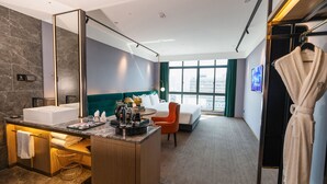 A hotel room with a bathroom, a bed, a seating area, and a view of the city. - NanNing Mandala Hotel (Nanning)