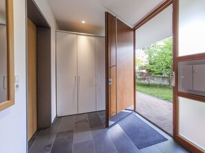 A hallway with a wardrobe, a door leading outside, and a tiled floor.
