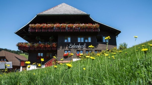 A two-story building with balconies adorned with flowers, labeled 'Elenhof.'
