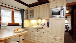 A kitchen with wooden cabinets, a microwave, a sink, and a window with curtains.