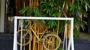 A white metal bench with a bicycle hanging on it, set against a bamboo backdrop. - Palatty's Resort (Aluva)