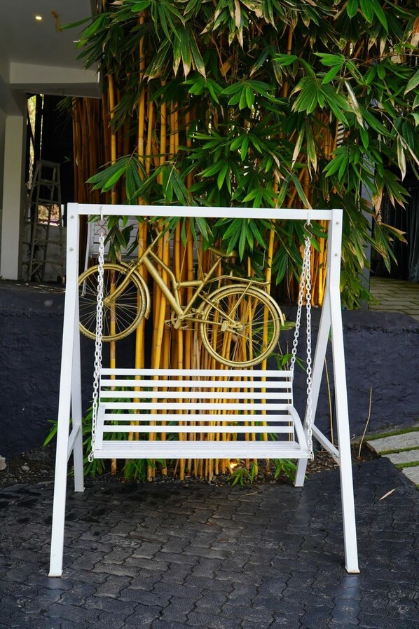 Un banc en métal blanc, sur lequel est accroché un vélo, le tout placé devant un décor de bambous.