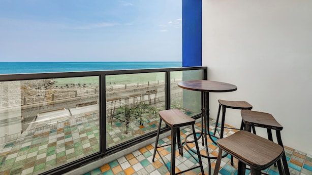 Ein Balkon mit Blick auf den Strand, einem Tisch und zwei Barhocker.