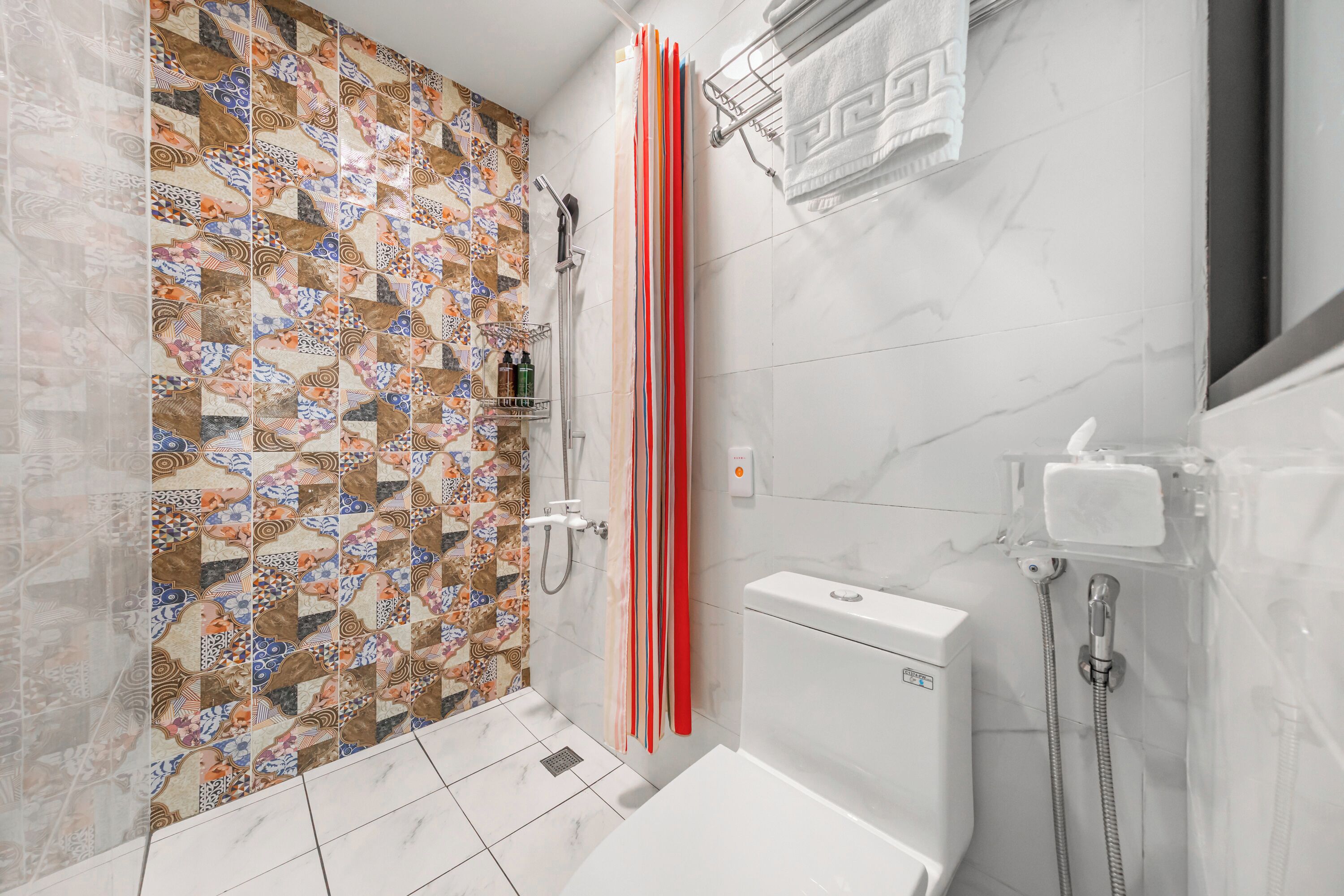A bathroom with a tiled shower area, a toilet, and a sink.
