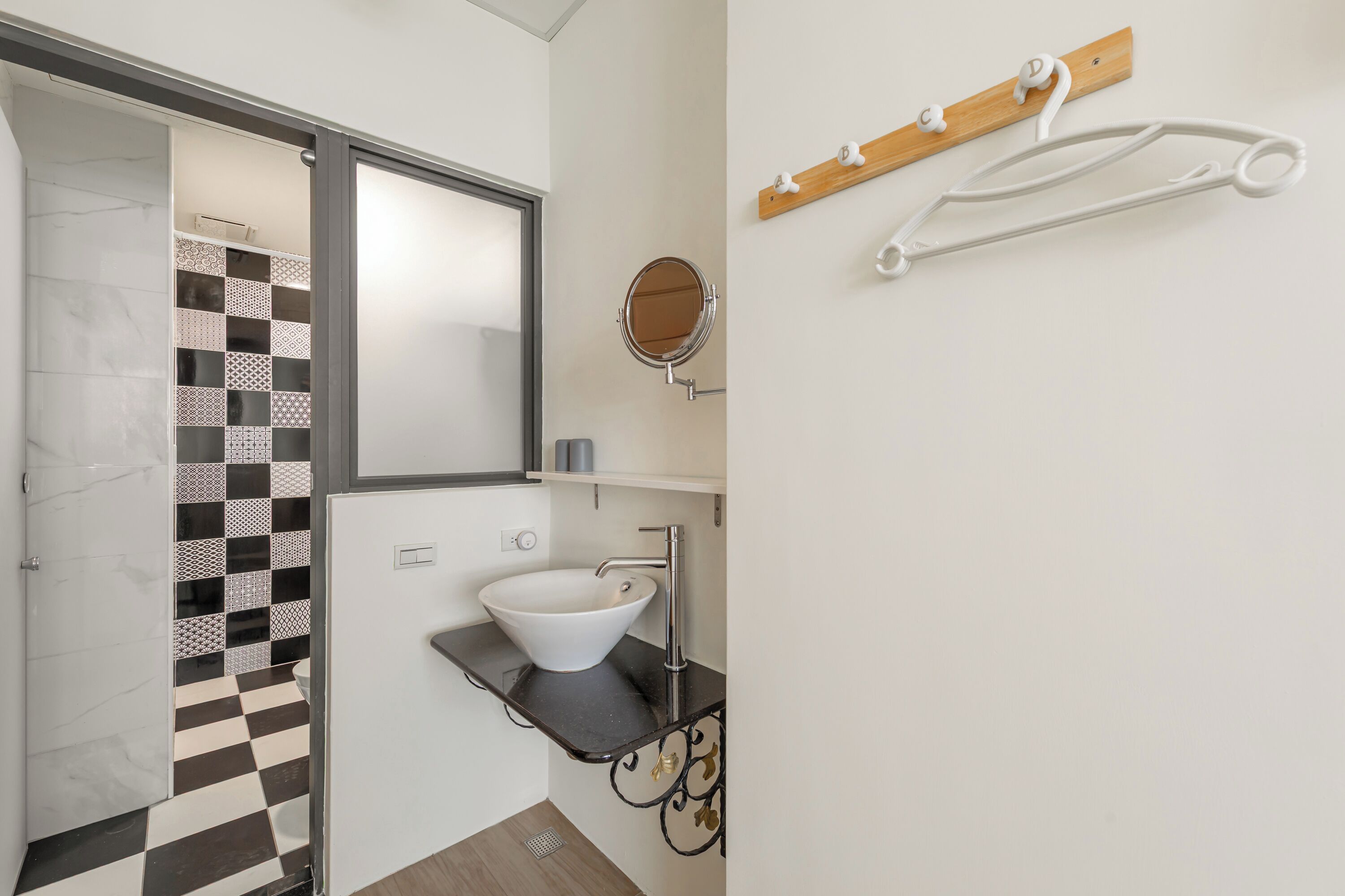 Une salle de bain avec un carrelage à motifs géométriques, un lavabo blanc, un miroir et un porte-serviettes.