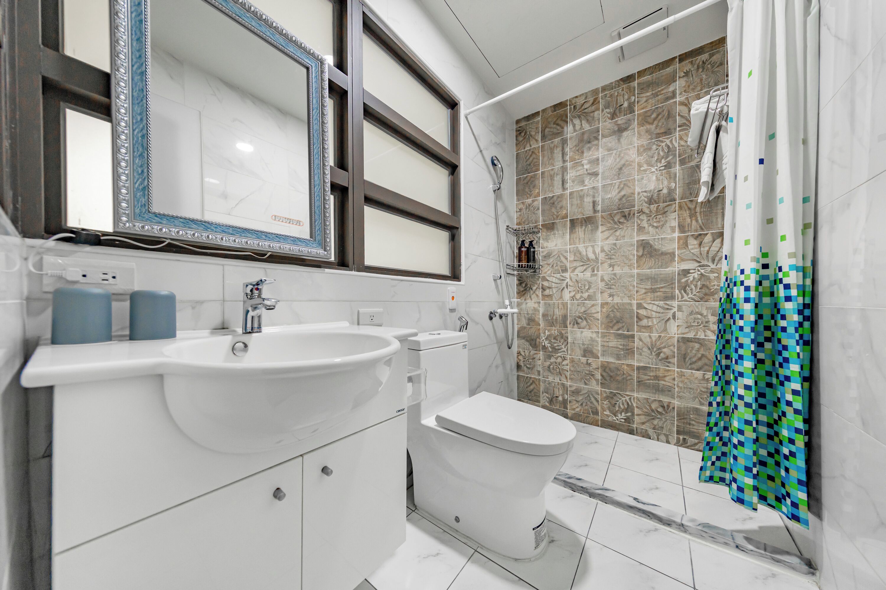 A modern bathroom with a large mirror, white sink, and toilet.