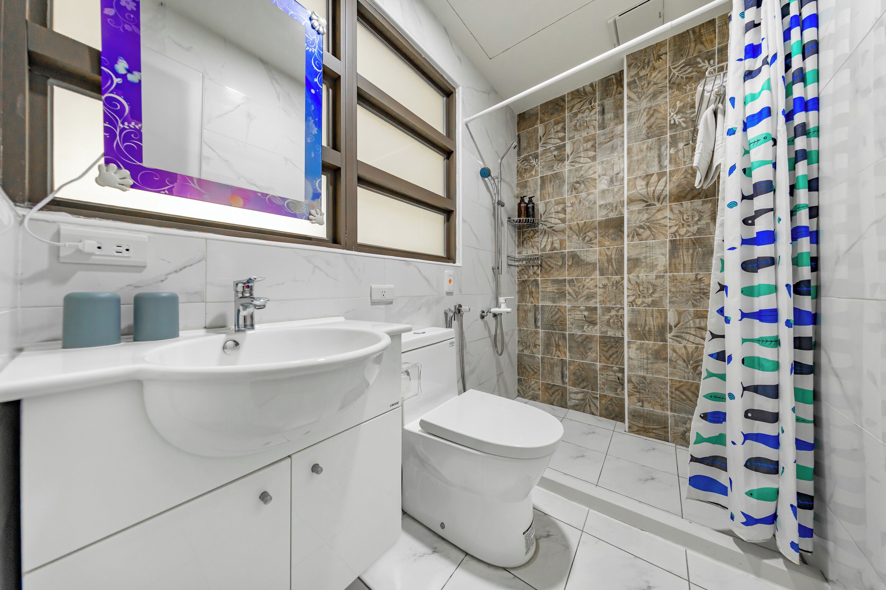 A bathroom with a white sink, toilet, and shower area.