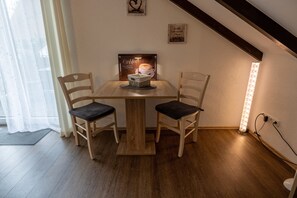 Een gezellige eethoek met een houten tafel en twee stoelen, een kunstwerk met koffie thema en een wandlamp.