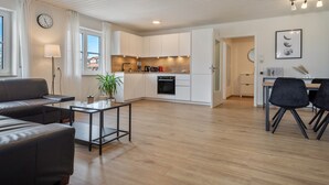 A modern apartment with a living area, kitchen, dining space, and a visible clock. - Apartment 'Bodenseenest' with Mountain View, Balcony and Wi-Fi (Meckenbeuren)