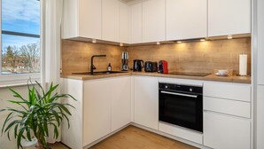 A modern kitchen with white cabinets, a wooden countertop, a built-in oven, and a window with a view of trees. - Apartment 'Bodenseenest' with Mountain View, Balcony and Wi-Fi (Meckenbeuren)