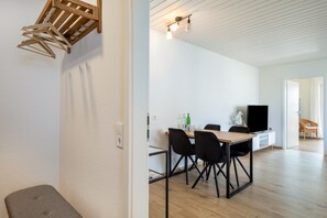 Un espacio habitable moderno con comedor, televisión y techo de madera.