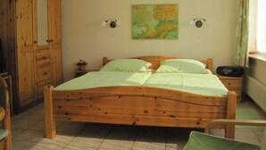 A wooden bed in a room with a cabinet and a painting on the wall. - Apartment 'Lotte Und Helmut Klanner' with Shared Terrace, Shared Garden and Wi-Fi (Daisendorf)