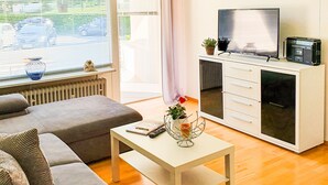 Una sala de estar moderna con un sofá, una mesa de centro, un televisor y un mueble.