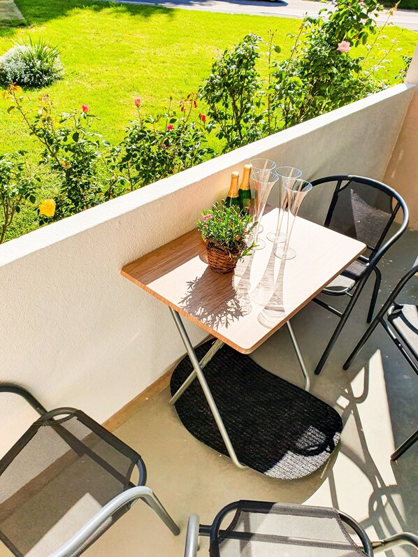 A balcony with a table set for two, featuring a basket of flowers and two champagne bottles.
