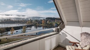 A balcony with a view of a lake, a chair, and a railing. - Apartment 'Studio' with Wi-Fi (Schluchsee)