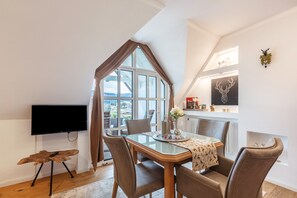A dining area with a table, chairs, a TV, and a window with curtains. - Apartment 'Seaview' with Shared Garden, Balcony and Wi-Fi (Schluchsee)
