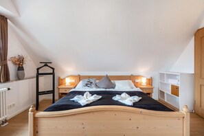 Une chambre à coucher avec un lit en bois, des tables de chevet, un radiateur, une étagère suspendue et une armoire.