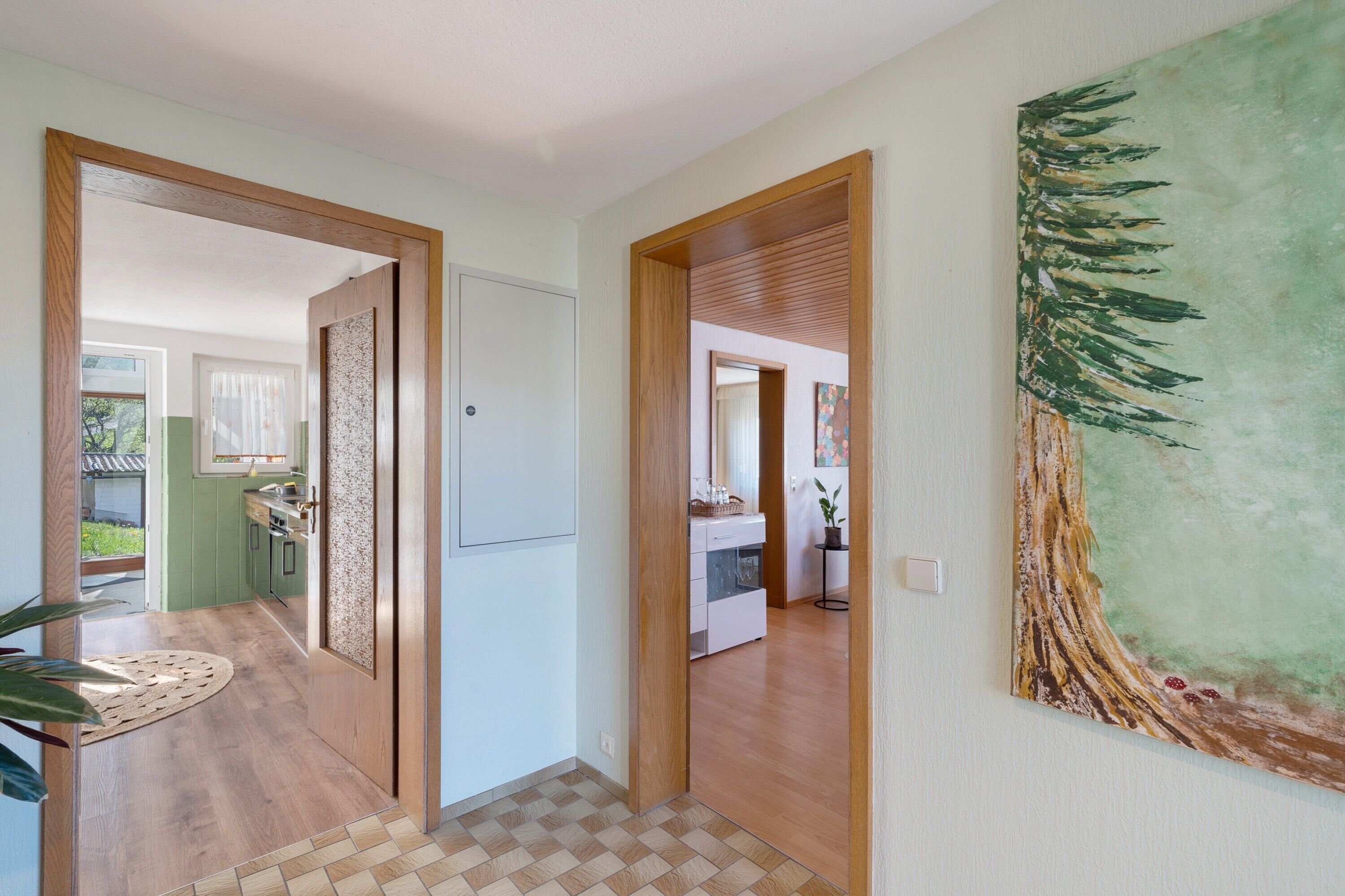 A hallway with wooden doors, a tiled floor, and a painting on the wall.