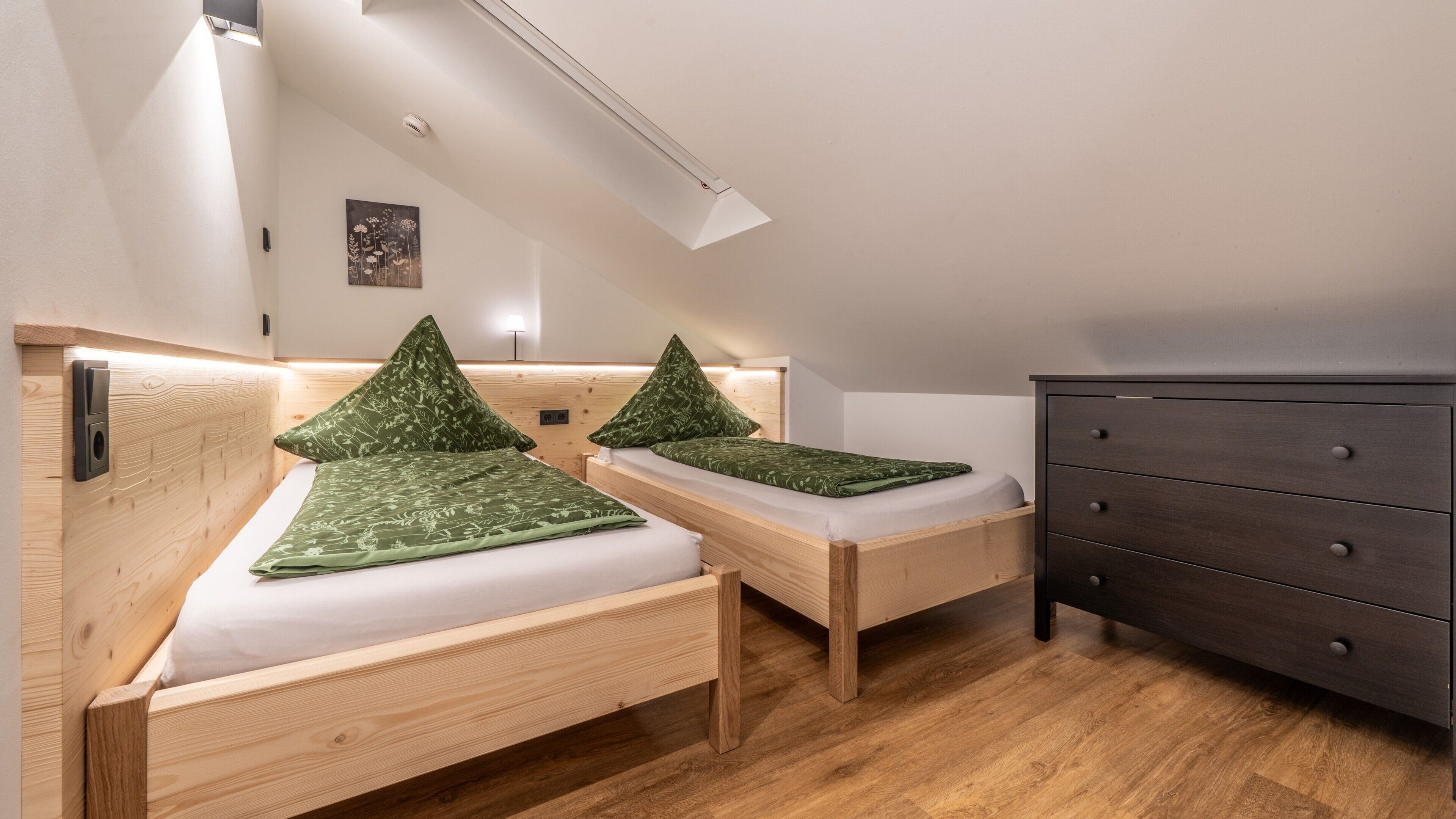 Un dormitorio con dos camas de madera, un aparador y un candelabro en el techo.