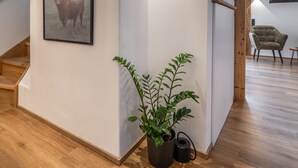 A modern interior with a wooden staircase, a framed picture of a bull, and a potted plant. - Chalet 'Hochsitz' incl. Königscard (Gaißach)