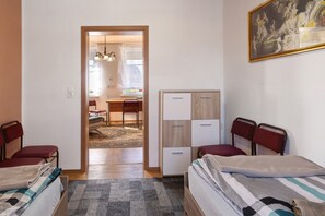 Un dormitorio con dos camas, un armario y un escritorio con una silla.
