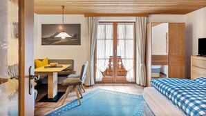 A room with a bed, a desk with a chair, a sofa, a window with curtains, and a painting on the wall. - Studio 'Burgberg' with Mountain View, Balcony and Wi-Fi (Mittenwald)