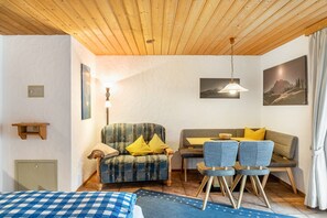 Une pièce comprenant un lit, un canapé, une table à manger avec des chaises, un luminaire suspendu et un tableau accroché au mur.
