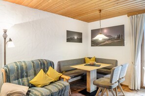 A cozy room with a sofa, a dining table, and chairs. There are two wall-mounted pictures depicting landscapes. - Studio 'Burgberg' with Mountain View, Balcony and Wi-Fi (Mittenwald)