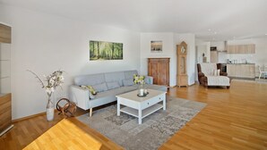 Een ruime woonkamer met een bank, salontafel en een eethoek met een stoel en tafel.