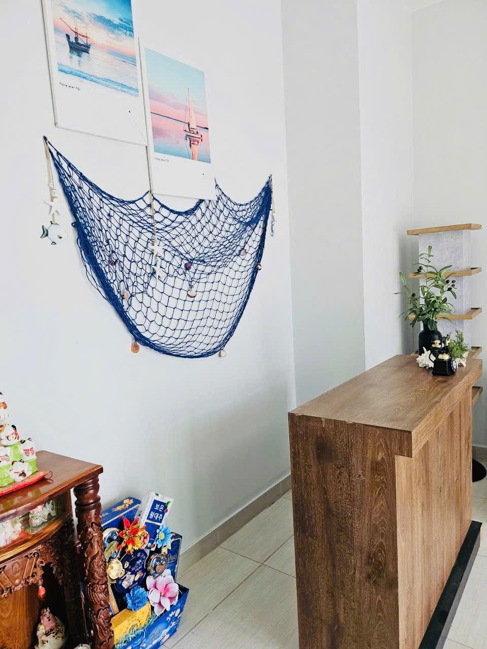 Ein Empfangsschalter mit Holzoptik, ein blaues Netz an der Wand und eine kleine Pflanze rechts.