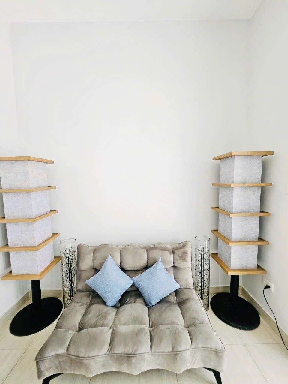 A room with a tufted sofa, two side tables, and a corner bookshelf.