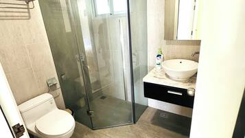 Un baño moderno con ducha de vidrio, inodoro y lavabo de encimera de mármol.