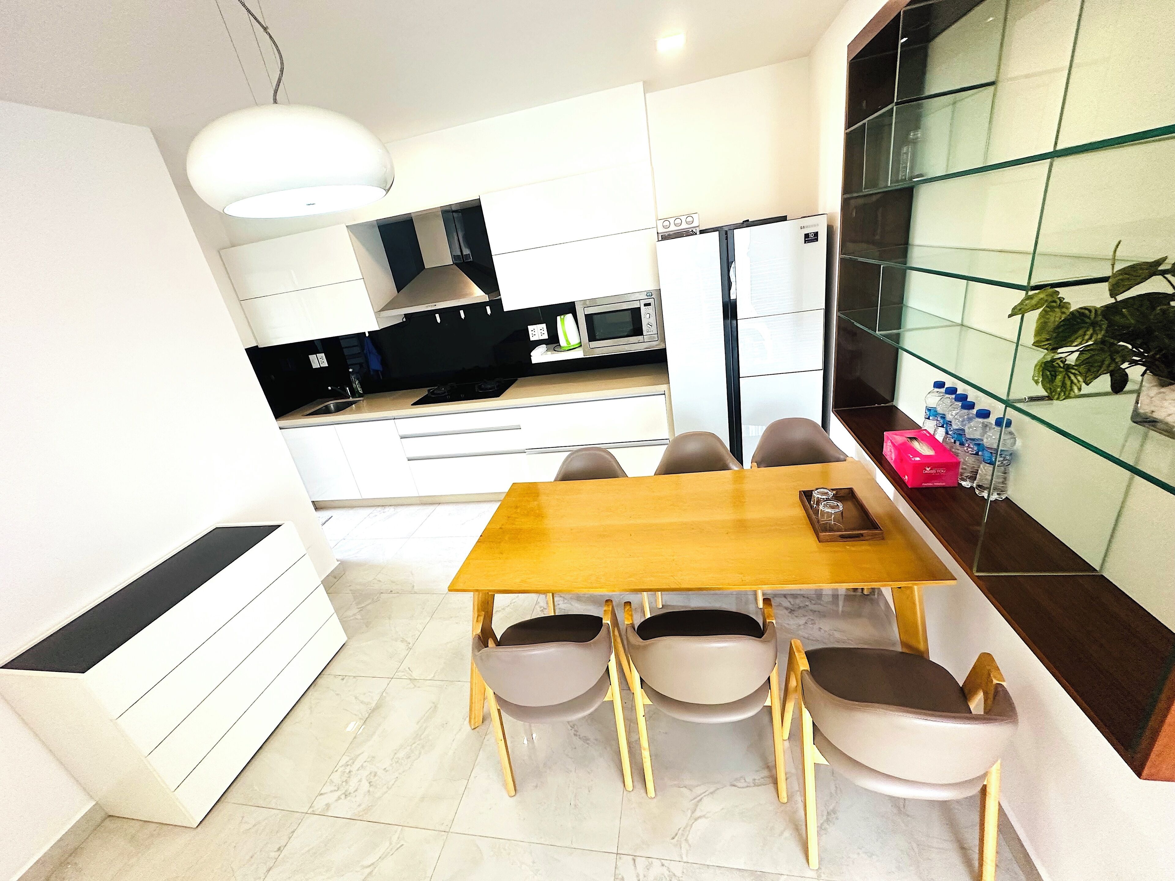 Una cocina moderna con comedor, que incluye una mesa y sillas de madera, un microondas y un refrigerador.