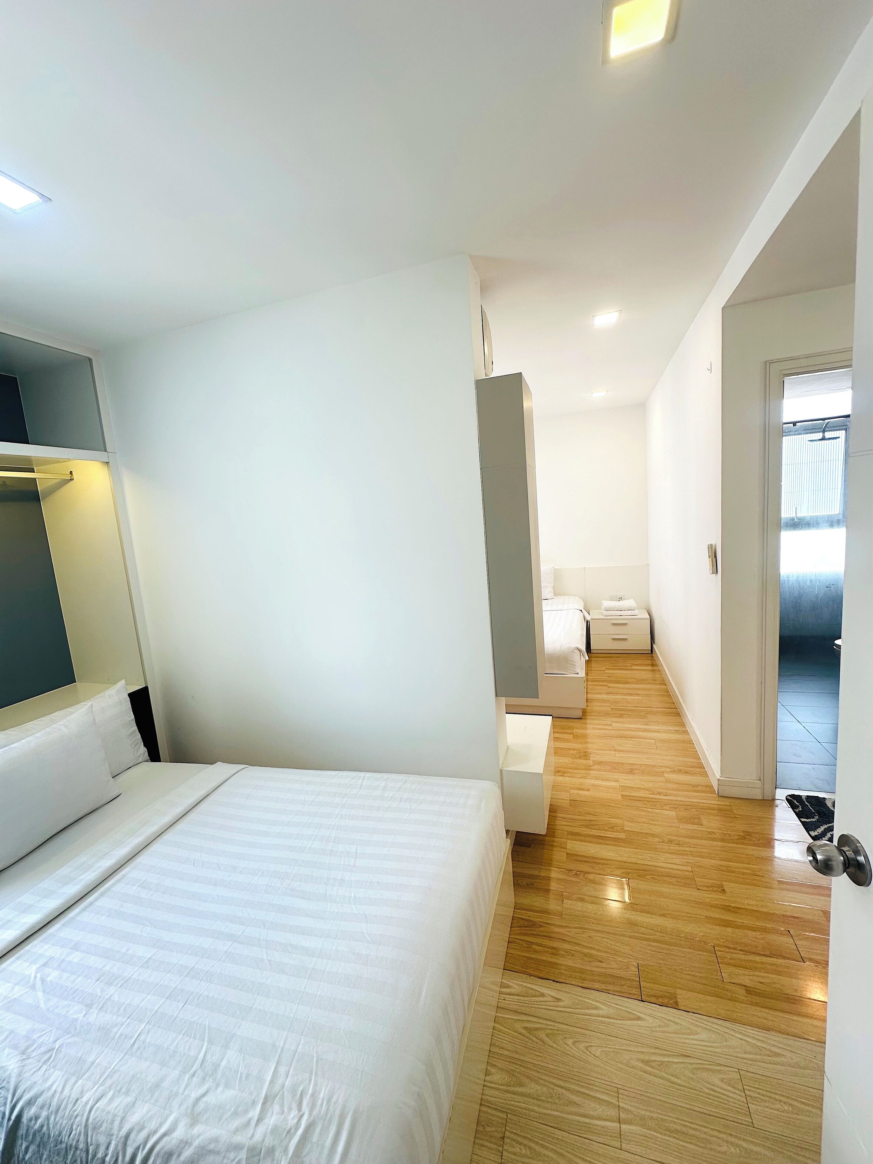 Een moderne hotelkamer met een groot bed, nachtkastje, kast en een zichtbare badkamer door een open deur.