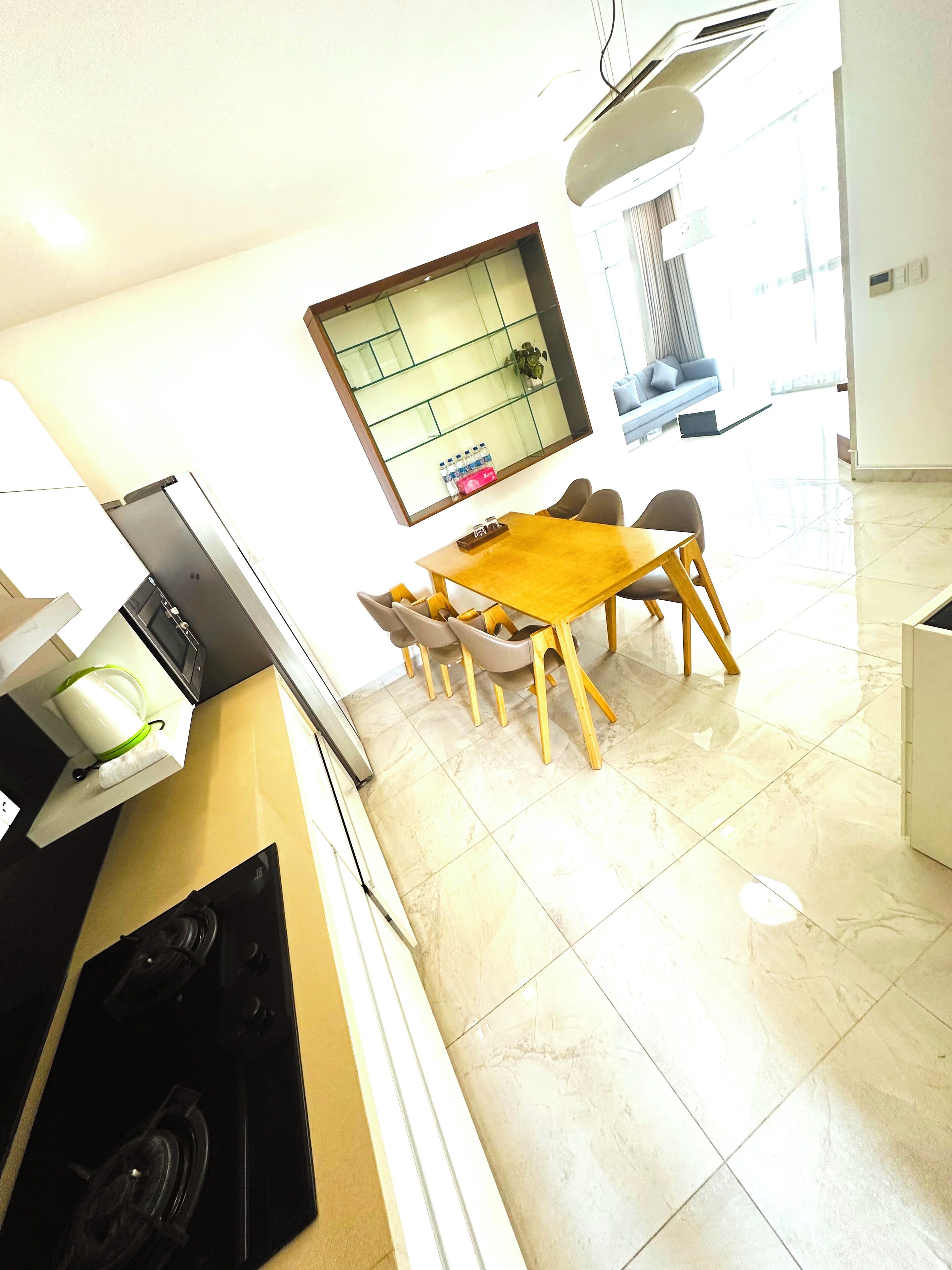 Een moderne keuken met een eethoek, met een groot raam, een inbouwfornuis en een eettafel met stoelen.