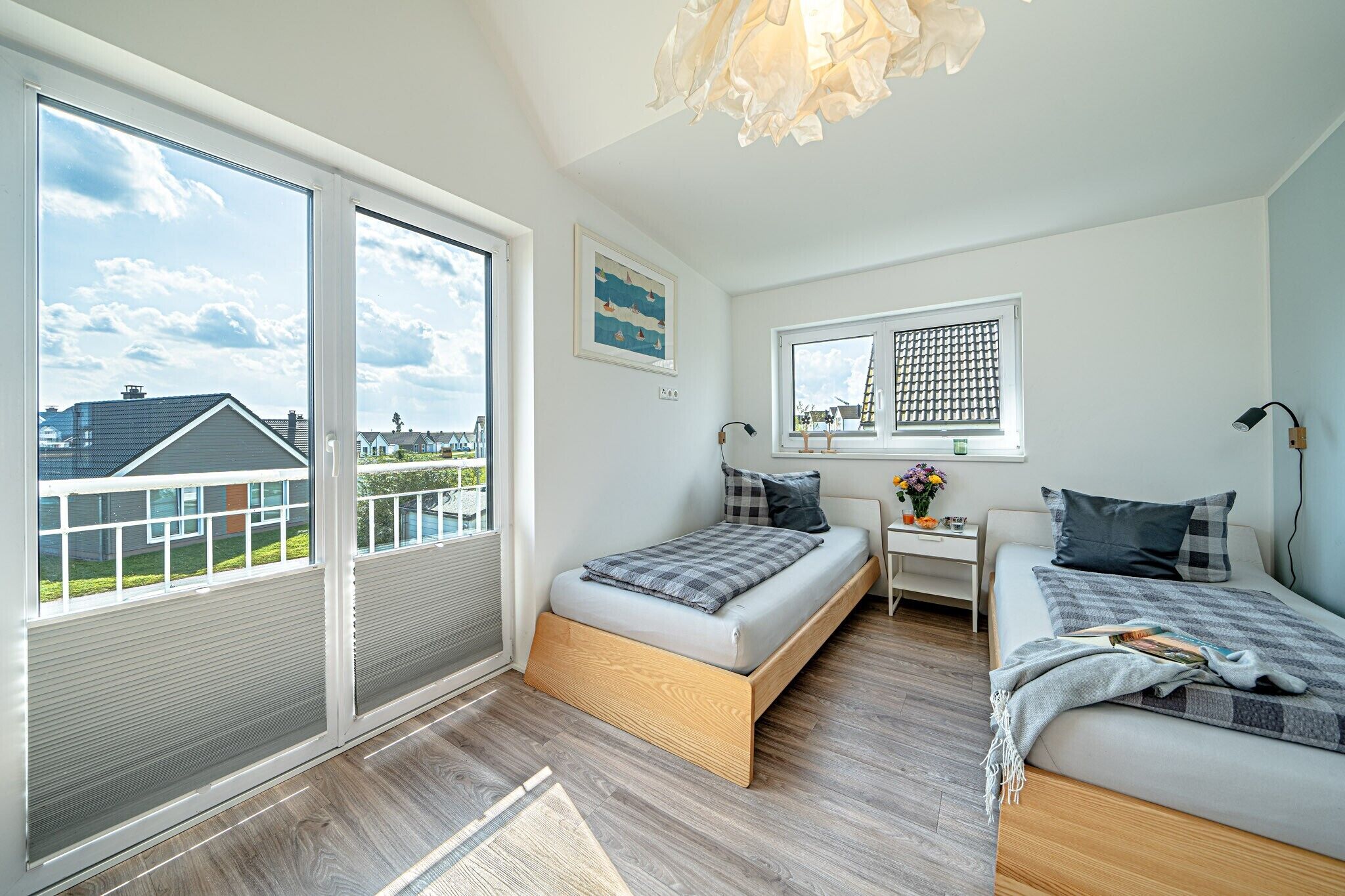 A bedroom with a bed, a desk, and a window with a view of buildings.