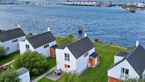 Una zona residencial costera con casas blancas, un muelle y un puerto deportivo al fondo.