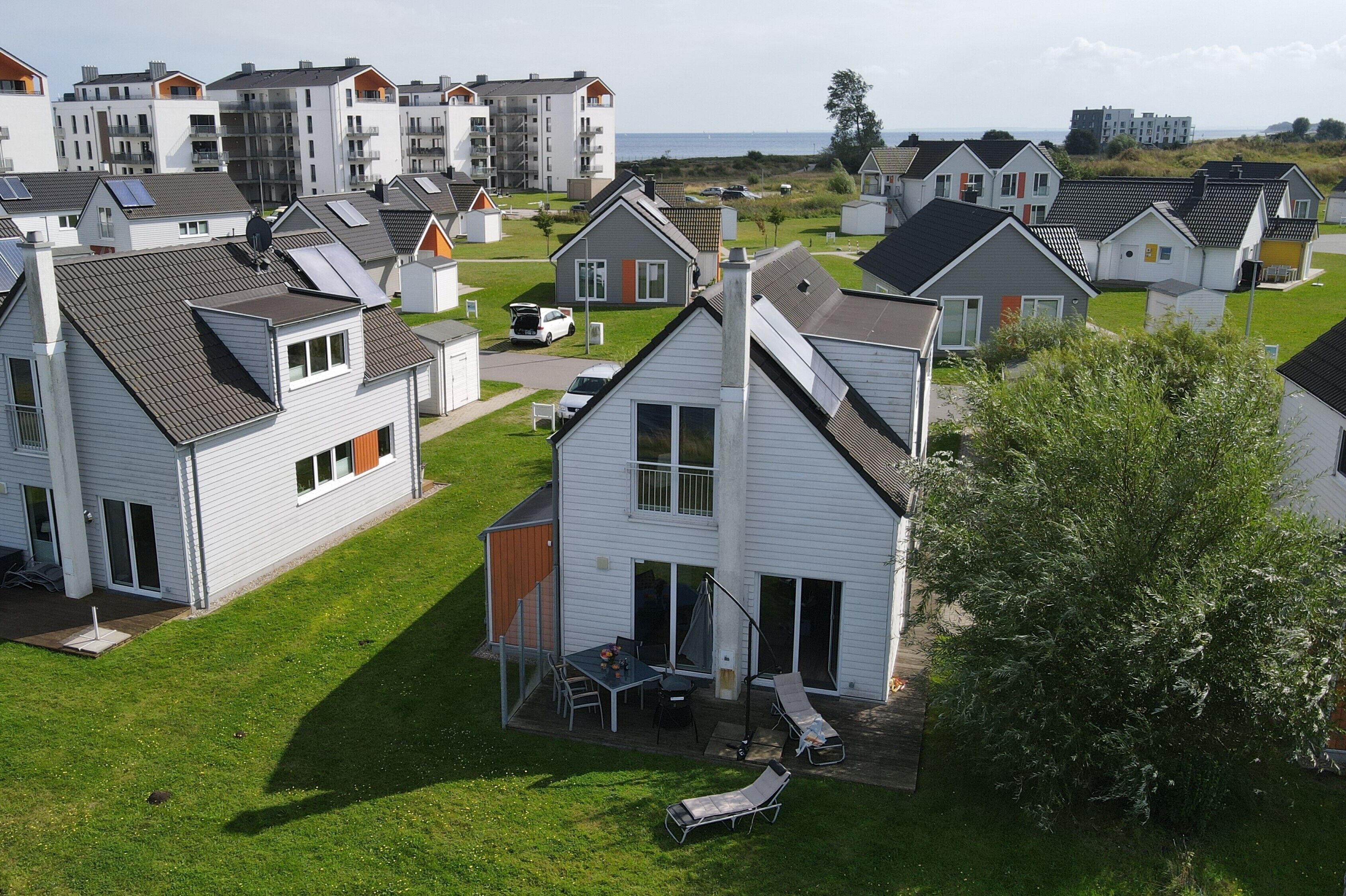 A residential area with multiple houses, some with balconies, and a grassy lawn.