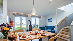 Un comedor con una mesa preparada para el desayuno, un sofá y una escalera.
