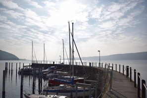 A marina with boats docked, a pier extending into calm water, and a distant shoreline.