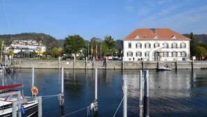A waterfront building with a red roof, docked boats, and a clear sky.