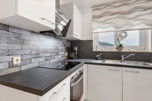 Eine moderne Küche mit Steinrückwand, einem eingebauten Backofen und einem Fenster mit Blick.