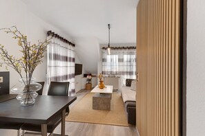 Ein modernes Wohnzimmer mit Essbereich, einer Couch, einem Couchtisch und einem Fernseher.