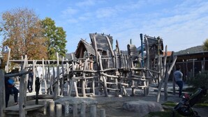 A playground with wooden structures and a stroller.