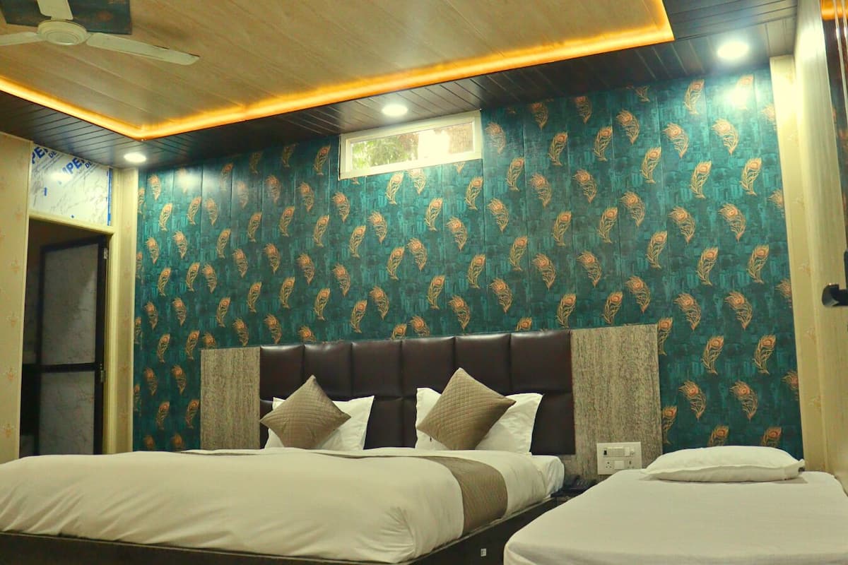 Quarto de hotel com duas camas, cabeceira escura, papel de parede estampado e ventilador de teto.