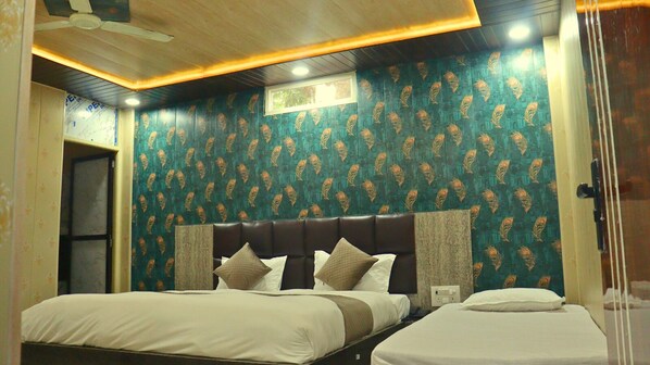 A hotel room with two beds, a dark headboard, patterned wallpaper, and a ceiling fan.