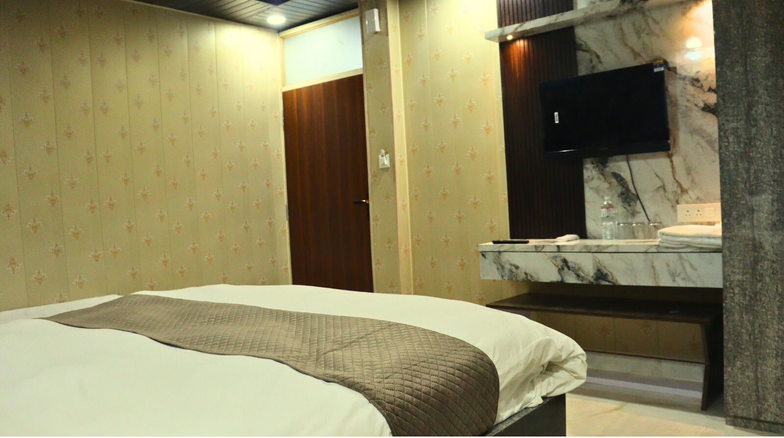Una habitación de hotel con una cama, un tocador de mármol y papel tapiz estampado.