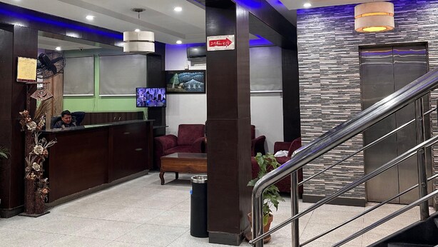 A hotel lobby with a reception desk, seating area, and a staircase. - Prime Inn Hotel (Rawalpindi)