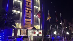 A hotel with a prominent sign reading "Inn Hotel Prime Inn Hotel" and multiple flags in front. - Prime Inn Hotel (Rawalpindi)